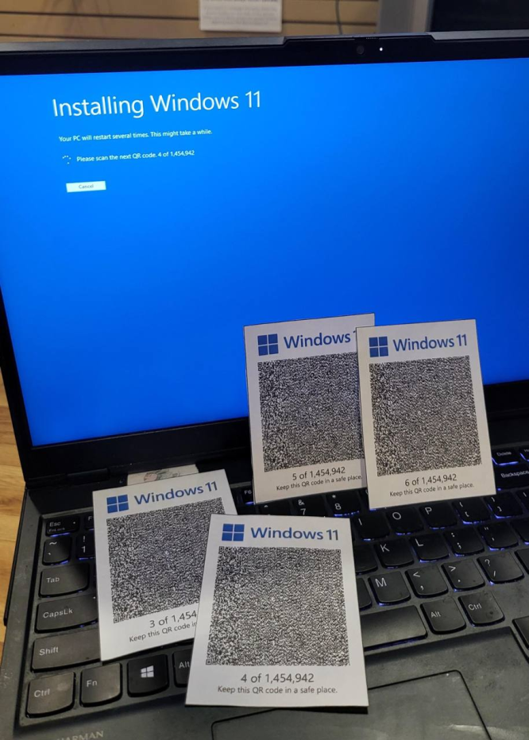 The image shows a laptop with a blue screen displaying the message "Installing Windows 11." The screen also instructs the user to scan the next QR code, with a number indicating the sequence. Four QR code cards are placed on the laptop's keyboard, each labeled "Windows 11" and numbered from 3 to 6 out of 1,454,942. The QR codes are black and white, with the Windows logo at the top. The laptop is on a wooden surface, and the keyboard is visible, with some keys like "Ctrl," "Fn," and "Shift" clearly seen. The background is a plain wall with a small white sign.

Provided by @altbot, generated privately and locally using Ovis2-8B